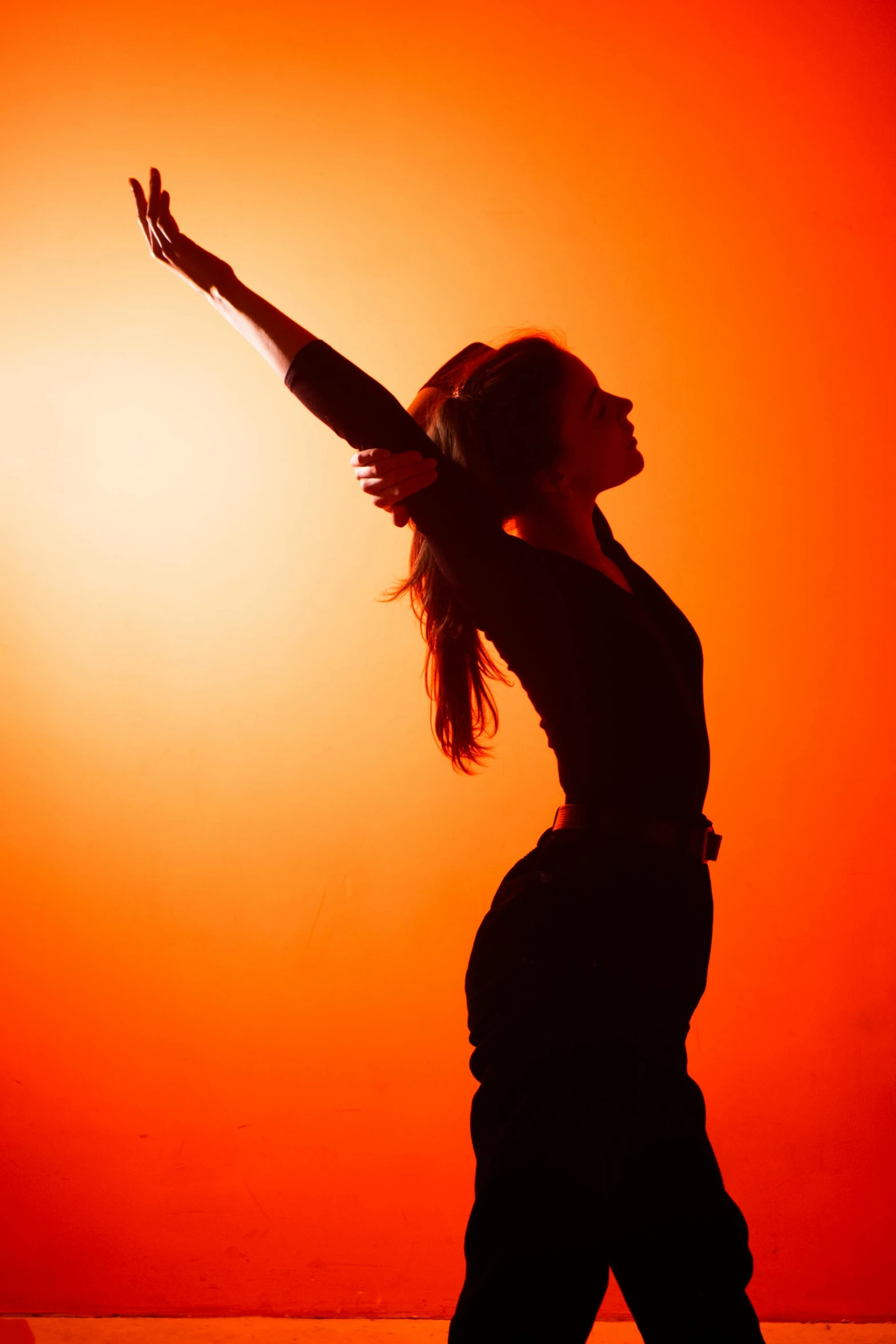 a woman is silhouetted against an orange background, doing a majestic pose, brightly-lit, rhythm, profile image