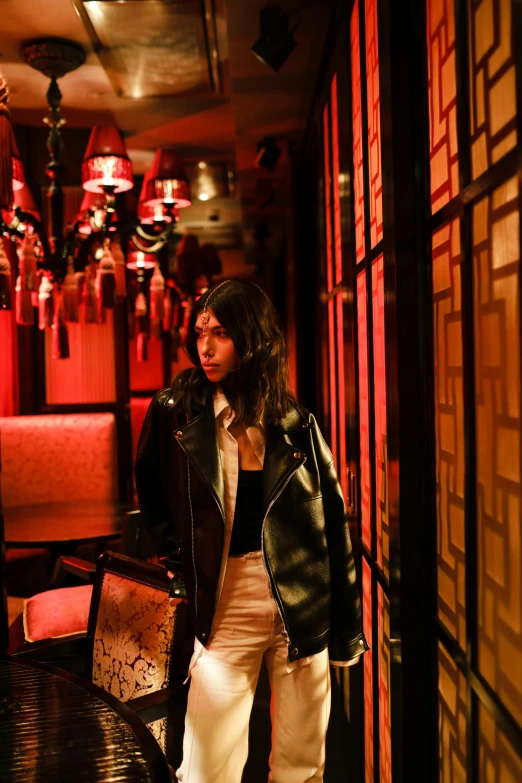 a woman standing in a dimly lit room, by Julia Pishtar, trending on unsplash, dressed in leather jacket, in tokio, red room, profile image