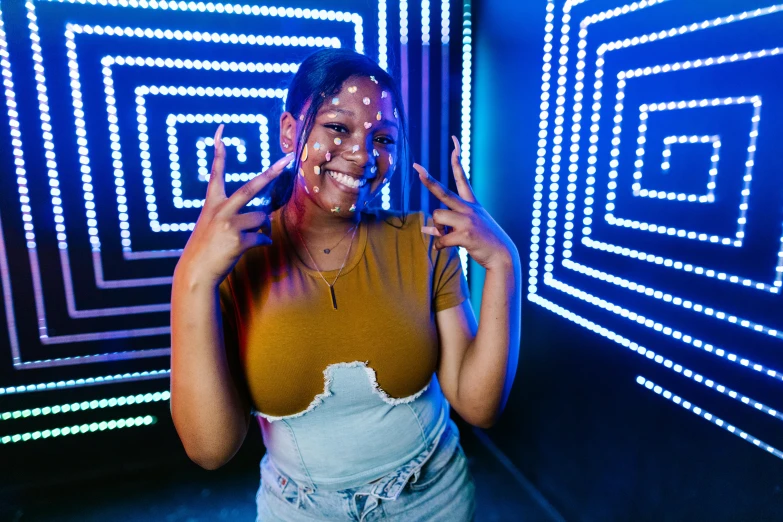 a woman standing in front of a wall covered in neon lights, a hologram, unsplash, interactive art, brown skin man with a giant grin, maze like, black teenage girl, holding it out to the camera