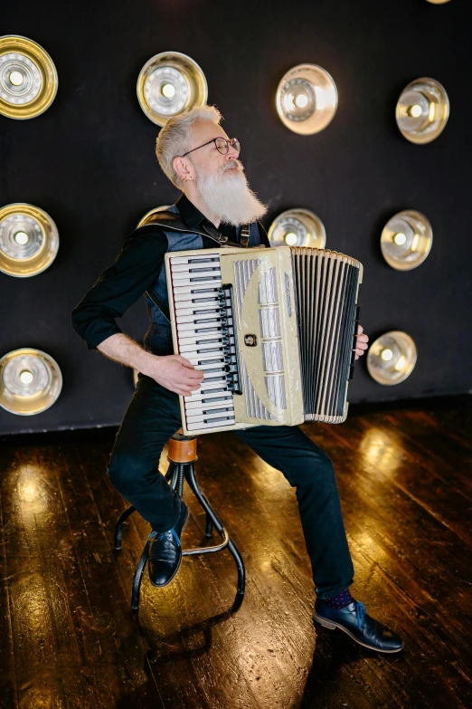 a man sitting on a stool playing an accordion, inspired by Ásgrímur Jónsson, happening, very long silver beard, youtube thumbnail, photoshoot, joel fletcher