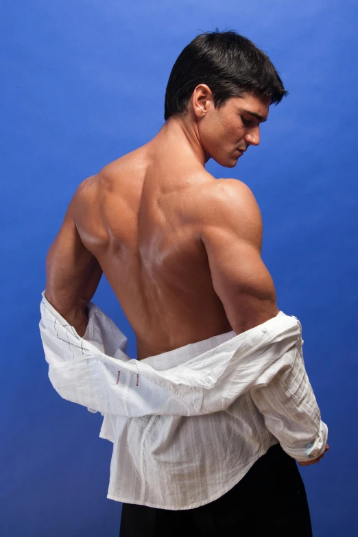 a shirtless man standing in front of a blue background, inspired by Roberto Ferri, wearing a white button up shirt, arched back, andres rios, fully covered in drapes