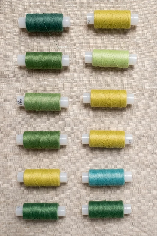 a bunch of spools of thread sitting on top of a table, by Alison Geissler, renaissance, green and yellow, eight eight eight, detailed product image, petite