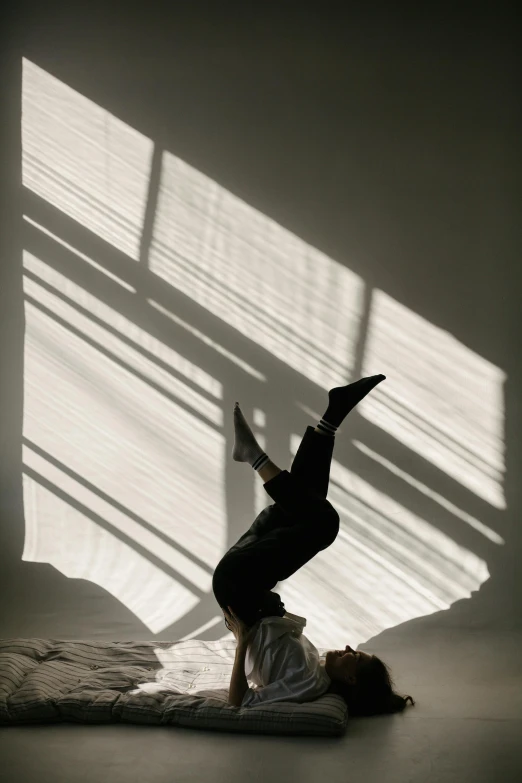 a person doing a handstand in front of a window, light and space, hood and shadows covering face, laying down, white backdrop, shot with sony alpha