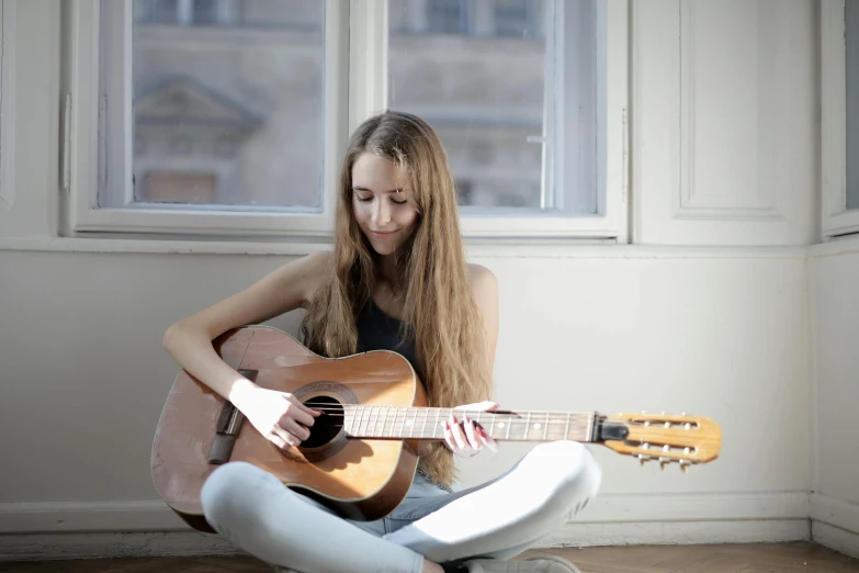 a woman sitting on the floor playing a guitar, pexels contest winner, antipodeans, greta thunberg, profile image, 1 6 years old, very thin