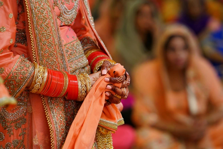 a close up of the hands of a bride, a digital rendering, by Manjit Bawa, pexels, orange robe, performance, photographed for reuters, islamic