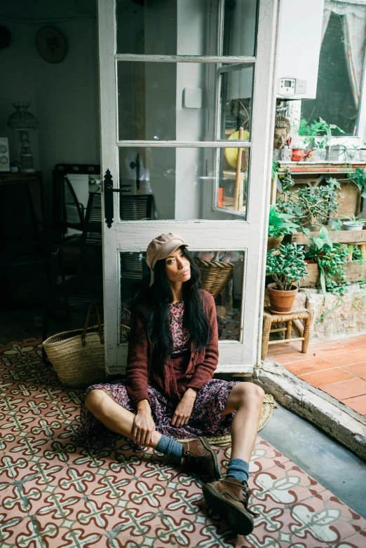 a woman sitting on the floor in front of a door, pexels contest winner, maroon hat, mai anh tran, standing near a window, al fresco