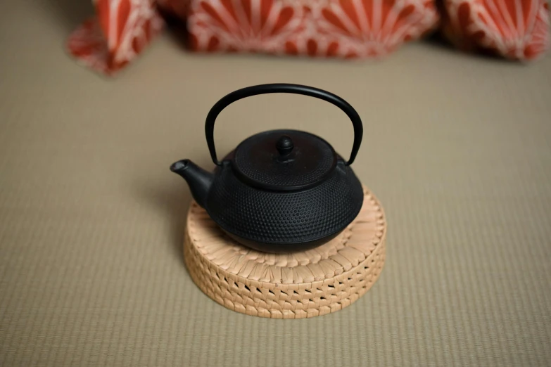 a black tea pot sitting on top of a coaster, inspired by Tōshi Yoshida, shin hanga, cast iron material, rin