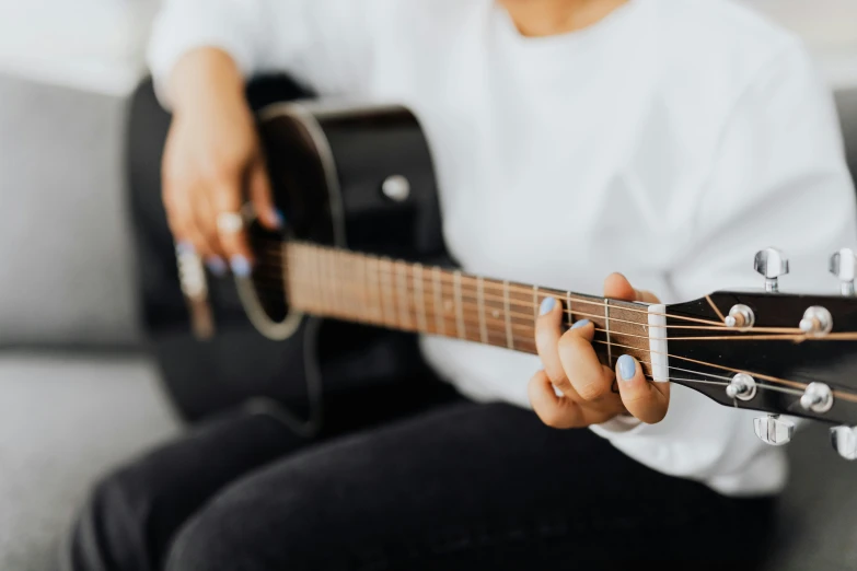 a woman sitting on a couch playing a guitar, pexels contest winner, private press, 🦩🪐🐞👩🏻🦳, middle close up, profile image, no - text no - logo