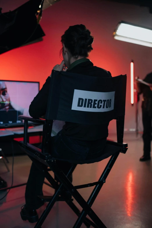 a man sitting in a chair in front of a tv, production ig studios, her back is to us, bts, fzd school of design