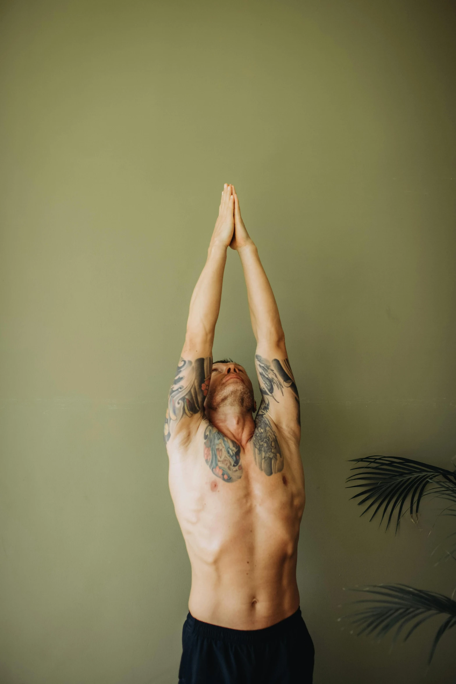 a man that is standing up with his hands in the air, a tattoo, unsplash, marjaryasana and bitilasana, green body, disrobed, 7 0 s photo