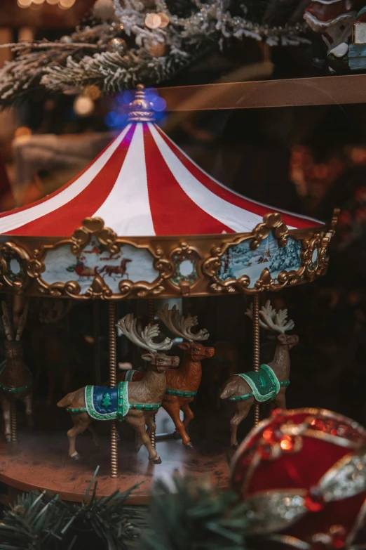 a close up of a carousel with a christmas tree in the background, paul barson, gold and red metal, a busy arcade, trinkets