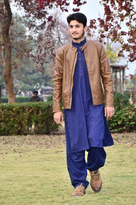 a man walking across a lush green field, by Riza Abbasi, dau-al-set, in a brown leather maxi jacket, dressed in blue, at college, golden blue outfit