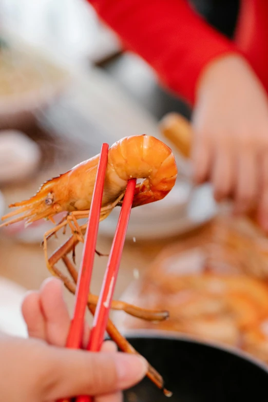 a close up of a person holding chopsticks near a shrimp, by Elizabeth Durack, festive atmosphere, full frame image, breakfast, iconic scene