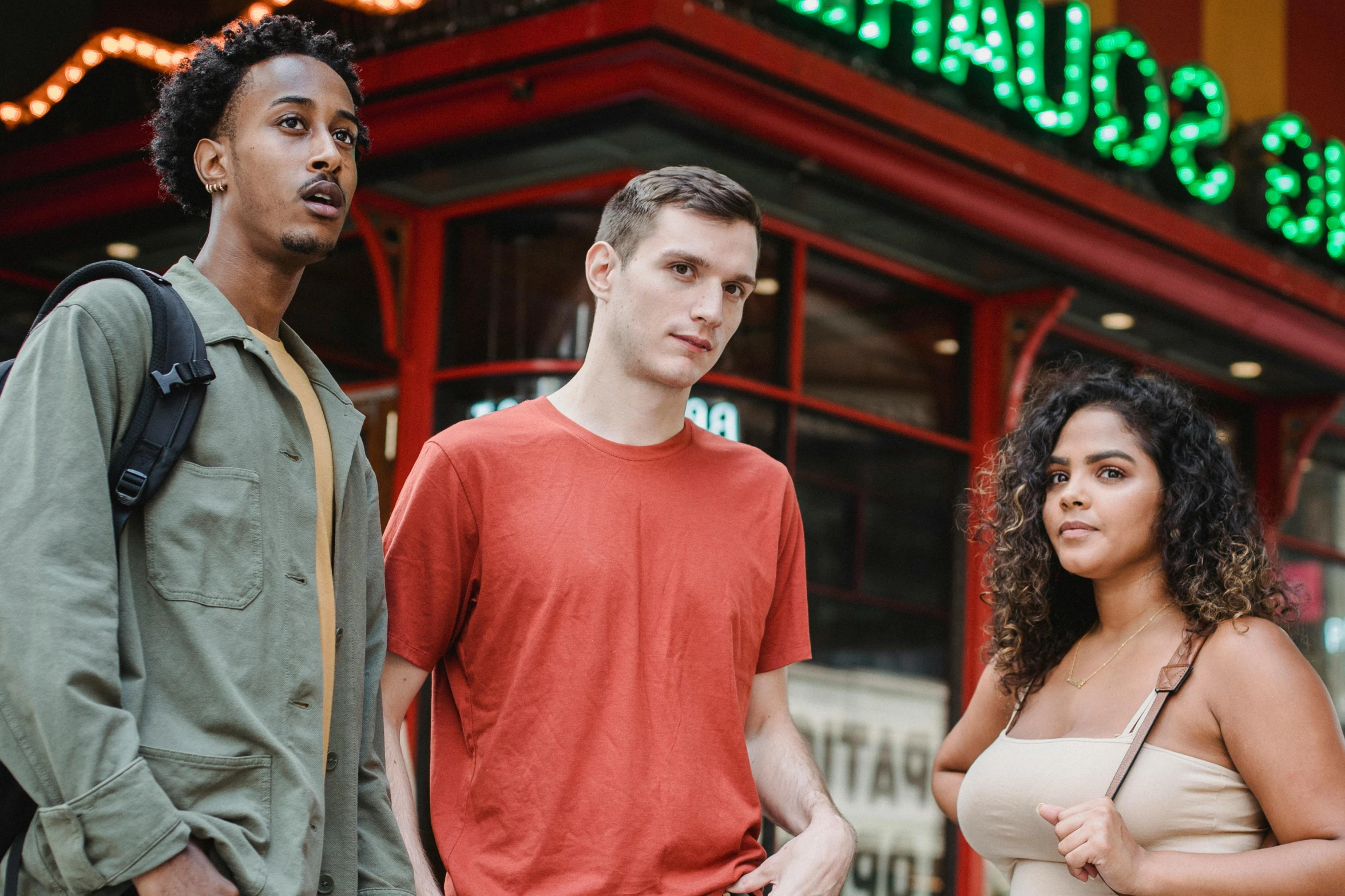 three people standing next to each other in front of a building, pexels contest winner, mixed race, band promo photo, merchants, background image