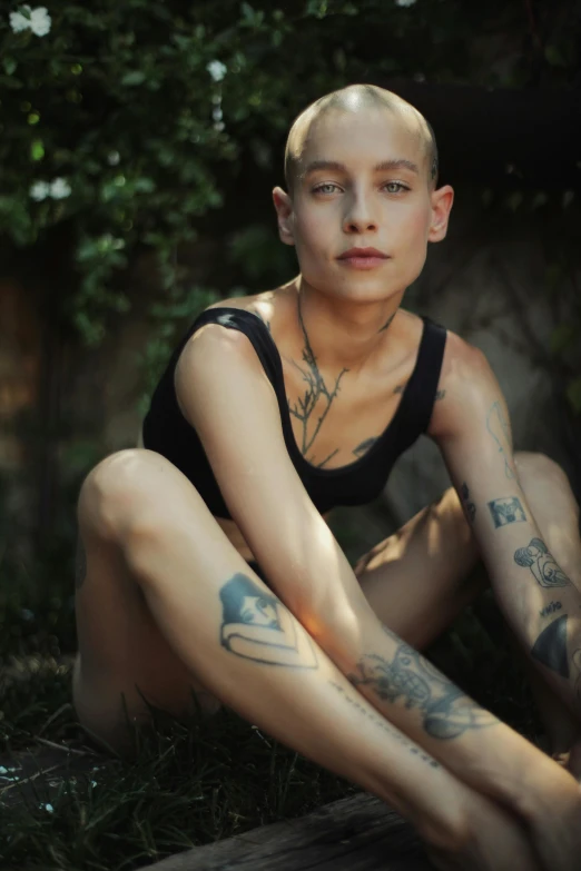 a woman sitting on top of a wooden bench, a tattoo, featured on reddit, antipodeans, non binary model, portrait of bald, in the yard, promo image