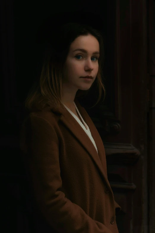 a woman in a brown coat standing in front of a window, a character portrait, pexels contest winner, tonalism, lilly collins, britt marling style 3/4, ( ( theatrical ) ), portrait young girl