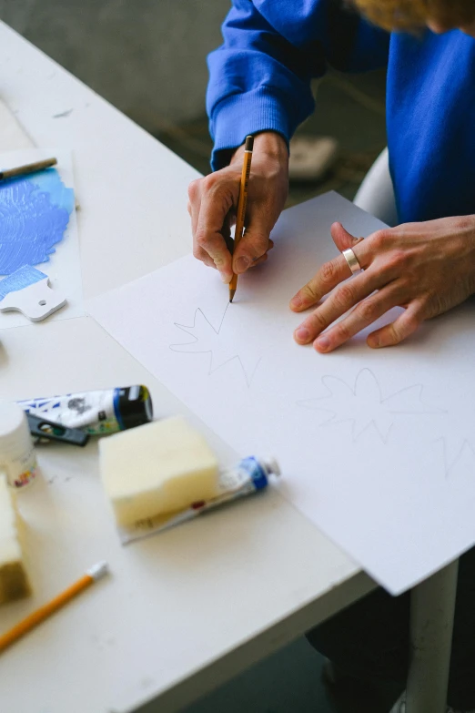 a woman is drawing on a piece of paper, a silk screen, arbeitsrat für kunst, soap carving, in blueprint form, depicting a flower, sleek hands