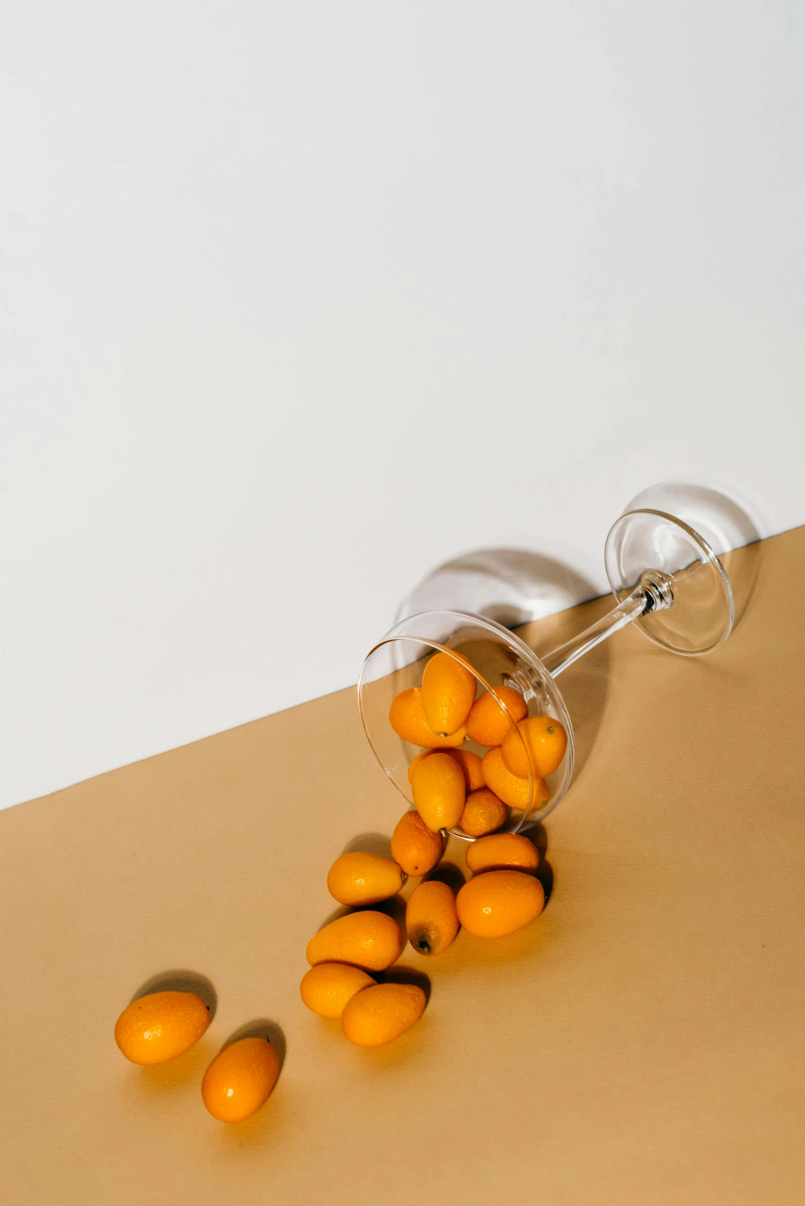 a glass filled with oranges sitting on top of a table, by Nina Hamnett, trending on unsplash, photorealism, holding maracas, silver and yellow color scheme, beans, minimalist composition