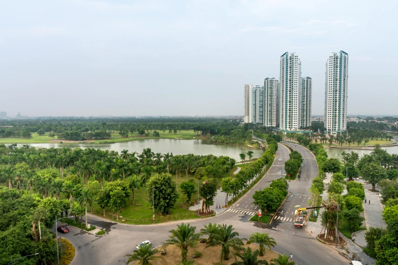 a view of a city from the top of a building, inspired by Cheng Jiasui, happening, in a park and next to a lake, vietnam, empty buildings with vegetation, golf course in background