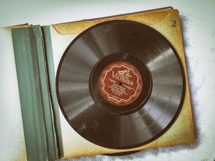 a record sitting on top of a table next to a book, an album cover, by Everett Warner, pixabay, vintage art deco, thumbnail, brown, packshot