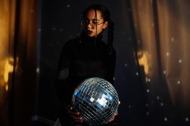 a woman holding a disco ball in her hands, by Julia Pishtar, pexels contest winner, holography, portrait of vanessa morgan, medium portrait top light, a young asian woman, indoor picture