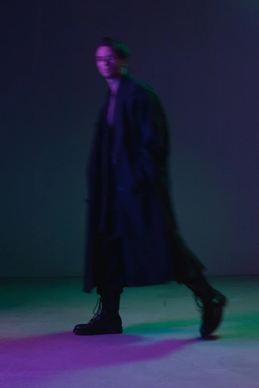 a man in a black coat is walking, an album cover, unsplash, neo-figurative, green and purple studio lighting, bella poarch, yohji yamamoto, dark. no text