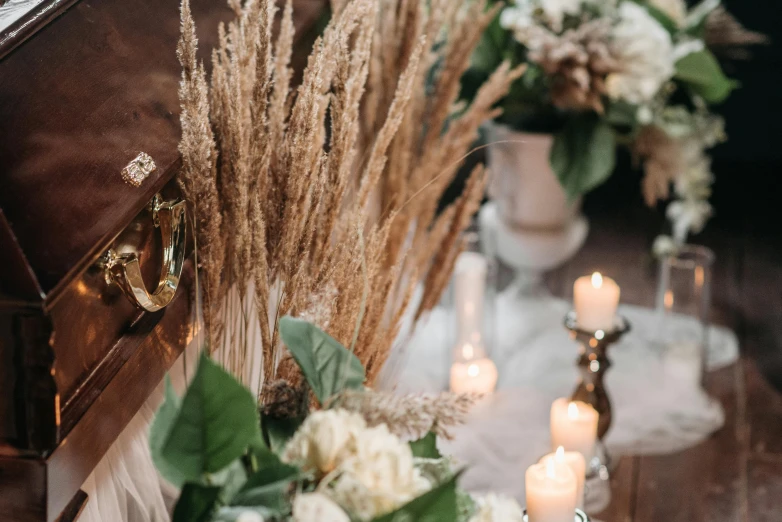 a suitcase sitting on top of a table next to a bunch of flowers, trending on pexels, renaissance, white candles, dry grass, white sweeping arches, candlelit restaurant table