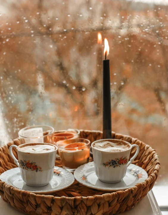 two cups of coffee sit on a tray in front of a window, by Lucia Peka, pexels contest winner, romanticism, dripping candles, snowstorm, thumbnail, brown color palette