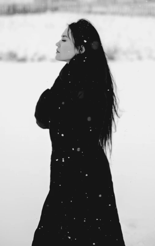 a black and white photo of a woman standing in the snow, a black and white photo, unsplash, portrait jisoo blackpink, woman with black hair, white sky, with black