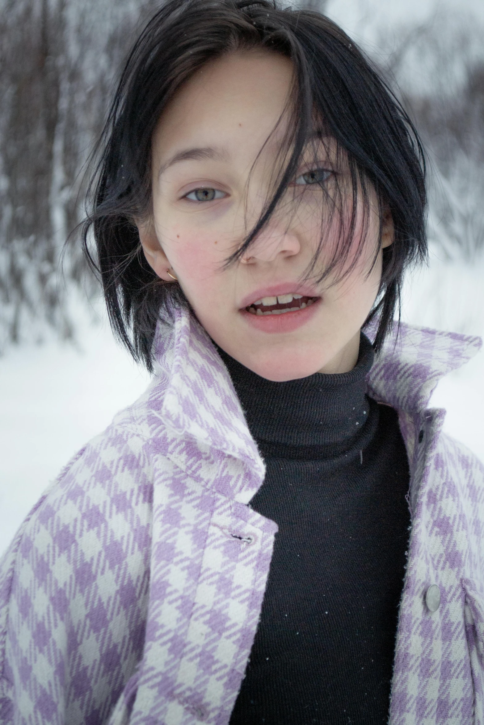 a woman standing in the snow with her hair blowing in the wind, an album cover, inspired by Cindy Sherman, trending on unsplash, hyperrealism, kiko mizuhara, pale skin and purple eyes, checkered spiked hair, lapland