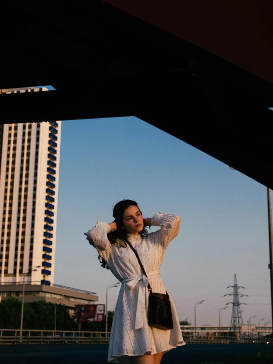 a woman standing in front of a tall building, white robe, ((sunset)), shot with sony alpha, bella poarch