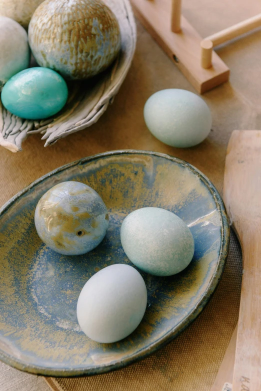 a bowl of eggs sitting on top of a wooden table, painted marble sculptures, soft blues and greens, teal palette.”, kek