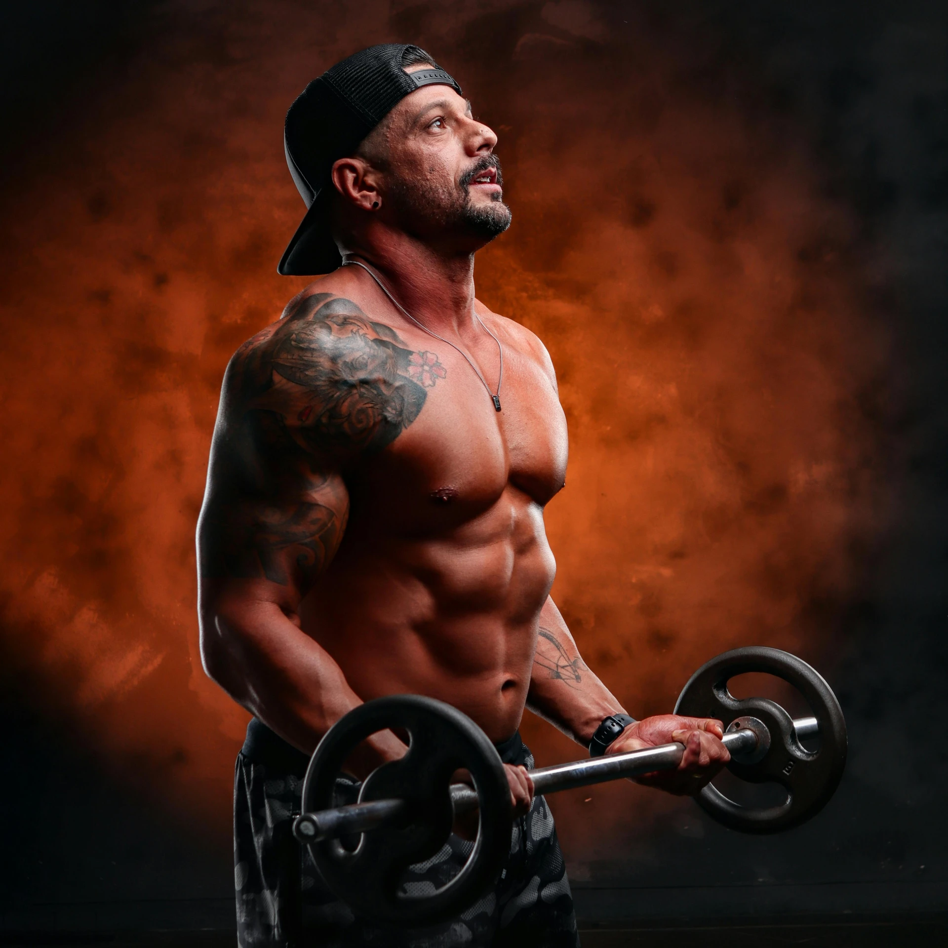 a muscular man holding a barbell on a dark background, a tattoo, pexels contest winner, in front of an orange background, profile pic, akt photography, danny trejo