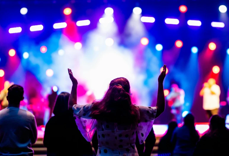 a group of people standing in front of a stage, by Tom Bonson, pexels, happening, holy themed, person in foreground, a colorful, boke