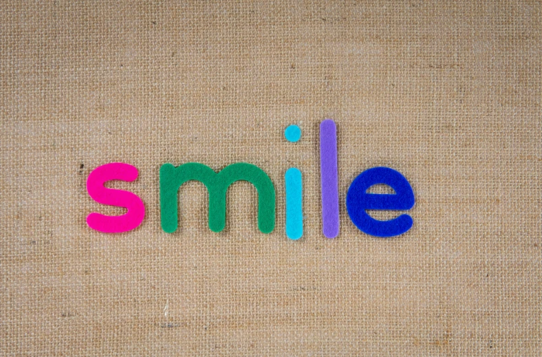 the word smile spelled in colorful plastic letters, trending on pexels, letterism, perfect smile vogue, good smile company, simplicity, smol