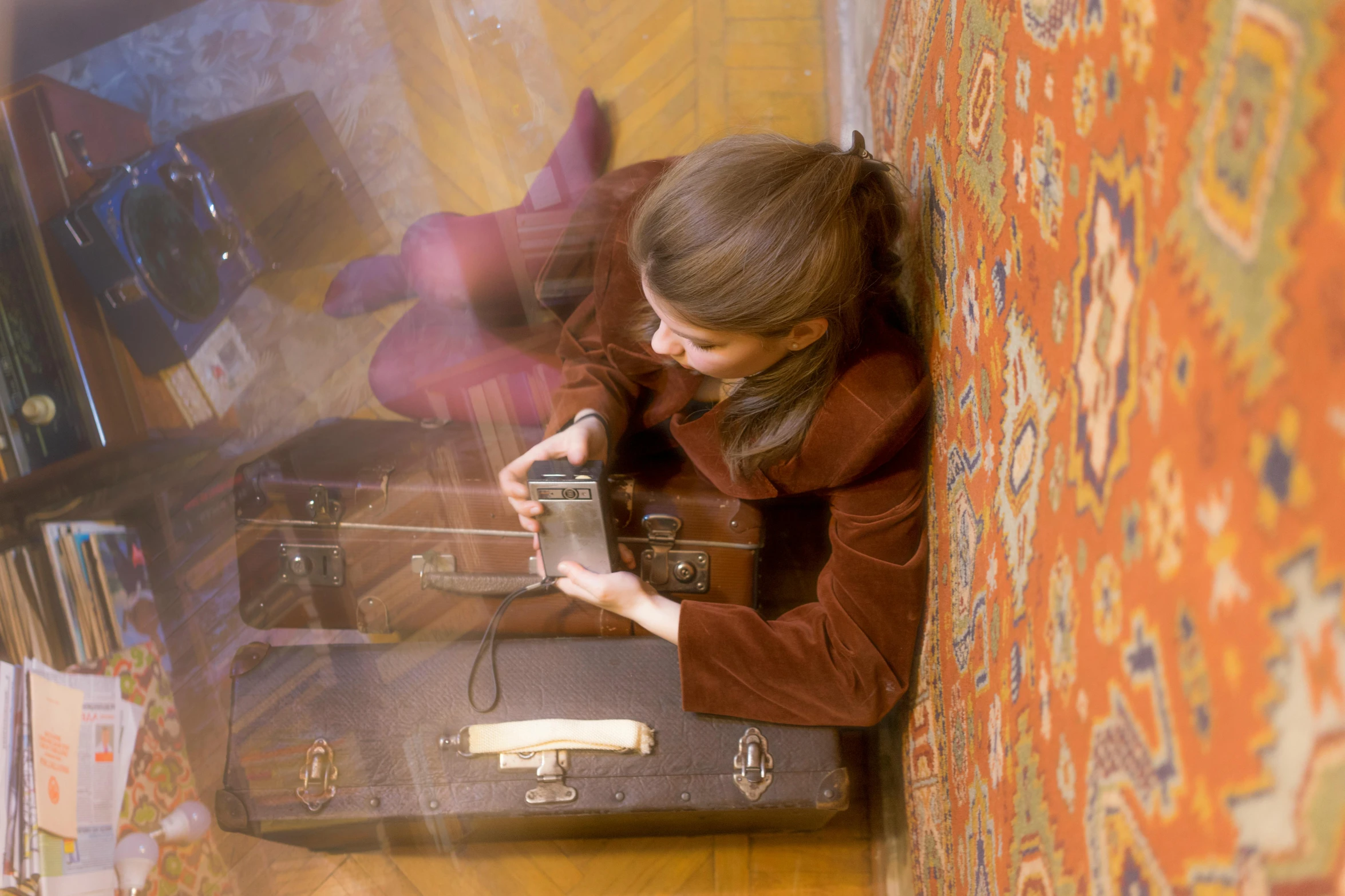 a woman leaning against a wall next to a suitcase, inspired by Balthus, pexels contest winner, persian carpets, camera looking down upon, seventies cinestill, teenager