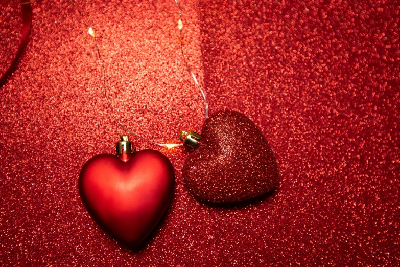 a red heart shaped ornament next to a wine glass, a photo, by Julia Pishtar, vibrant red background, sparkles and glitter, connected to heart machines, closeup - view