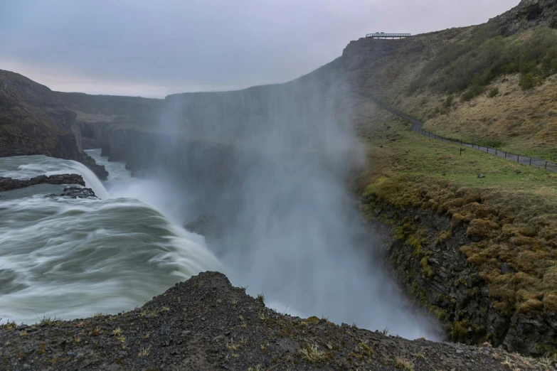 a large waterfall flowing over a lush green hillside, by Terese Nielsen, pexels contest winner, hurufiyya, foggy water, whirlpool, grey, extreme panoramic