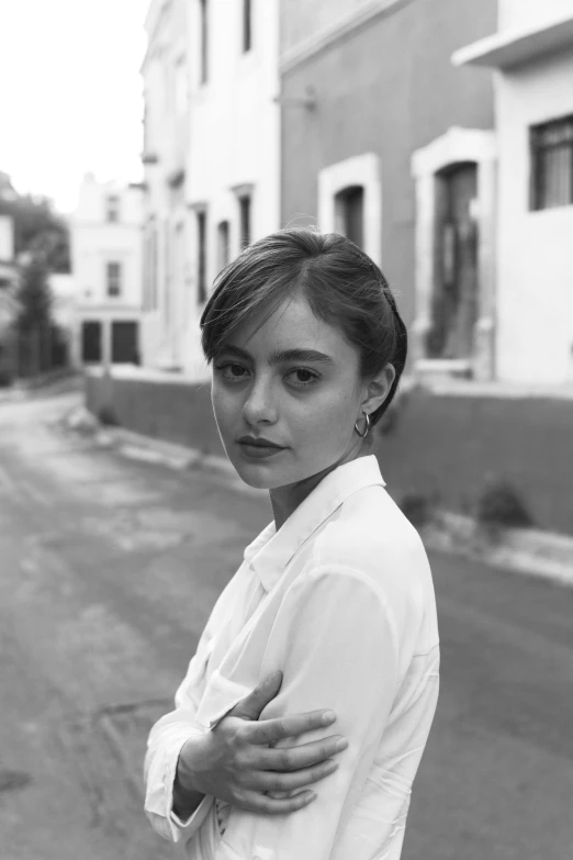 a woman standing in the middle of a street, a black and white photo, portrait sophie mudd, wearing a white button up shirt, sydney hanson, beautiful mexican woman