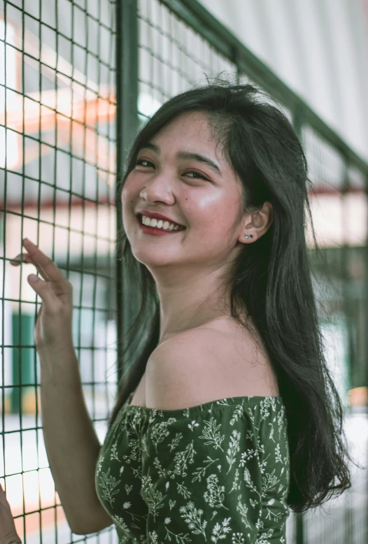 a woman in a green dress leaning against a fence, by Bernardino Mei, pexels contest winner, smiling young woman, 🤤 girl portrait, halfbody headshot, ruan cute vtuber