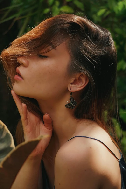 a beautiful young woman standing next to a man, inspired by Elsa Bleda, trending on pexels, butterfly jewelry, left ear, in a jungle, asian girl