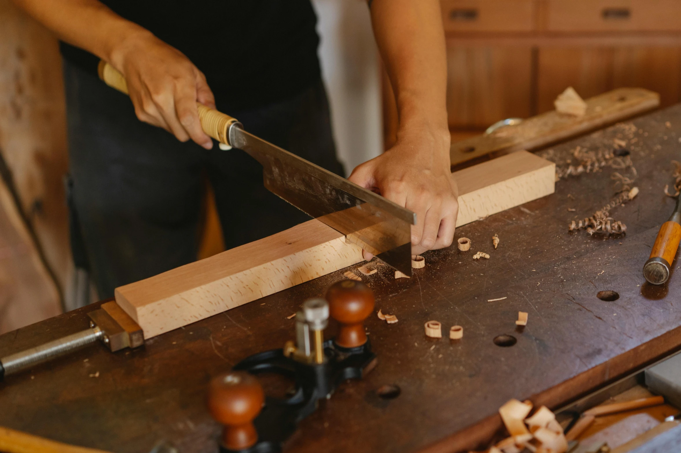 a person cutting a piece of wood with a large knife, trending on pexels, arts and crafts movement, nanae kawahara, rectangle, brown, thumbnail