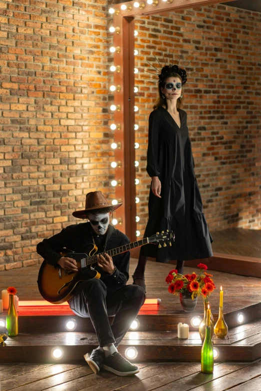 a man playing guitar next to a woman in a black dress, pexels contest winner, international gothic, dia de muertos dress and make up, standing in a cantina, ao dai, on an empty stage from above