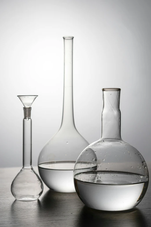 a group of glass vases sitting on top of a table, scientific glassware, water drops, detailed product image, alembic