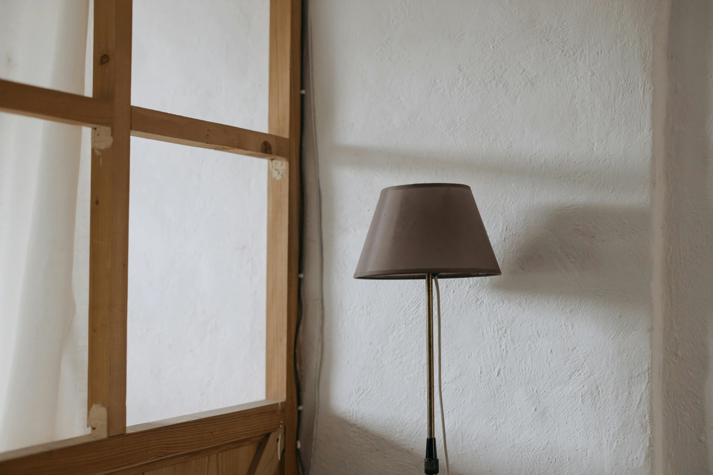 a lamp sitting on top of a table next to a window, by Niels Lergaard, muted brown, lined in cotton, mid-20s, small room