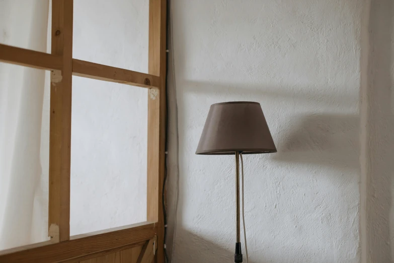 a lamp sitting on top of a table next to a window, by Niels Lergaard, muted brown, lined in cotton, mid-20s, small room