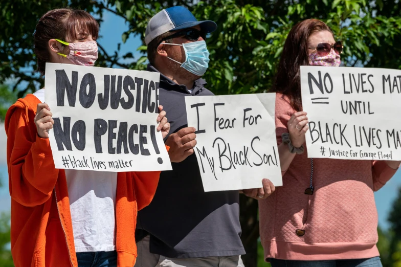 a group of people standing next to each other holding signs, by Washington Allston, pexels, renaissance, white man with black fabric mask, orange and black, mourning family, 3 - piece