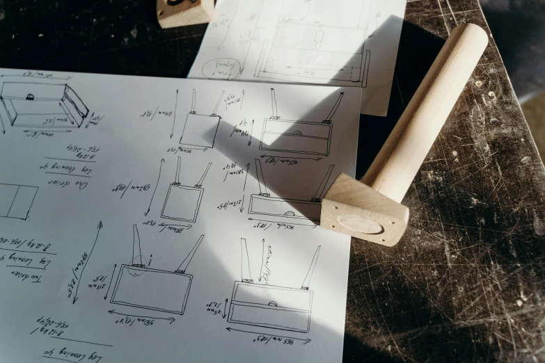 a piece of paper sitting on top of a table, a drawing, holding a hammer, wooden supports, classic product design, thumbnail