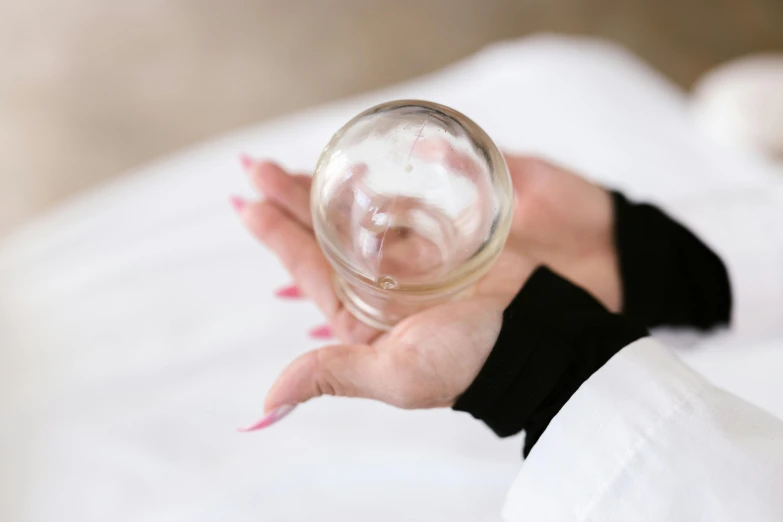 a close up of a person holding a glass, inspired by Louise Bourgeois, unsplash, cervix awakening, high angle view, translucent sphere, 1 5 0 ml lens