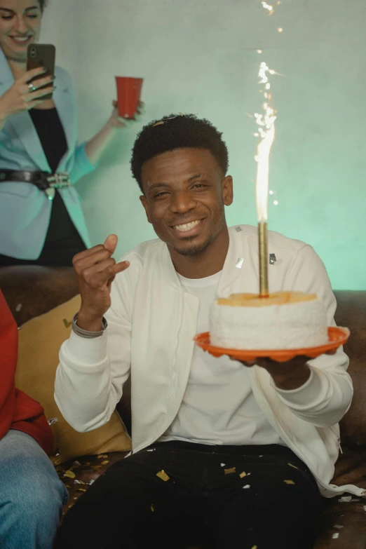a man sitting on a couch holding a cake, 2 1 savage, holding a candle, trending on tiktok, b - roll
